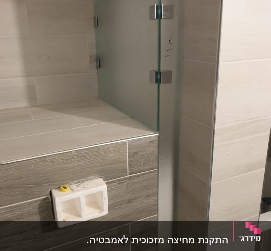 זכוכית חלבית עם צירים מתכתיים על קיר אריחים